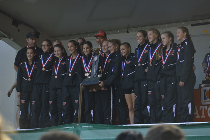 At the awards ceremony, the girls cross country team receives their 3rd place team trophy.