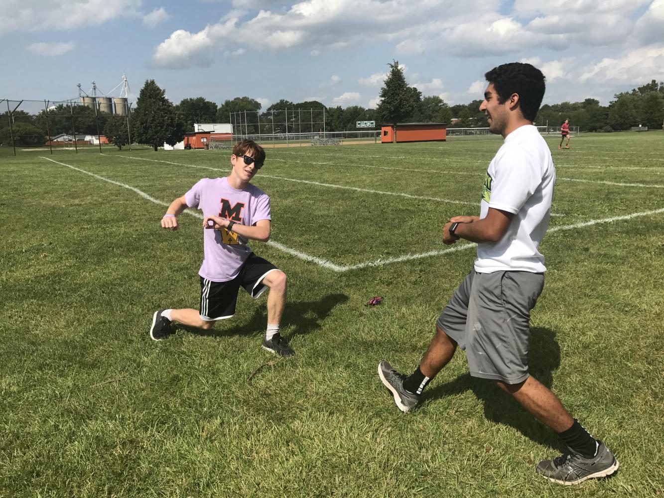 Seniors Mick Ward and Tony Cisneros perform the lunge matrix as part of their warmup before cross country practice on Aug. 24.