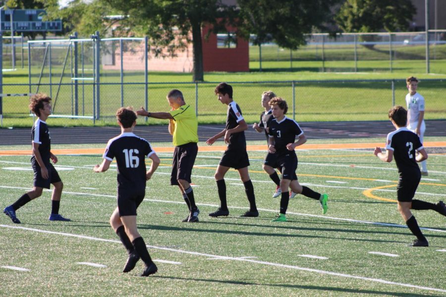 The team runs back into position when Michael Ruettiger, junior, scores with 13 minutes left of the first half. The referee signals that the ball is to be placed back into the center of the field.