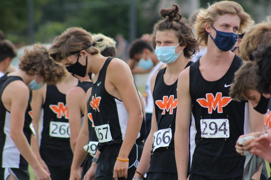 Bryce Harris, Robby Hajduk, Vincent Van Eck and the rest of the varsity boys cross country team line up at the starting line before they race at home against Oswego East on Aug. 29. Runners mask up until seconds before the starting gun goes off. Minooka won the meet, 24-34.