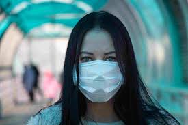 A woman wears a mask in public, protecting herself and others around her. 
