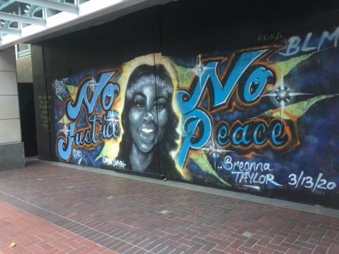 A spray painted mural on the outside of the Pioneer Place Mall in Portland, Ore., shows Breonna Taylor with the words No Justice No Peace.